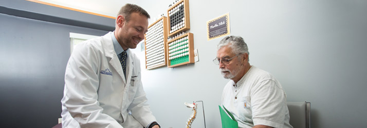 Chiropractor Wichita KS Chris Schroeder Chiropractor Chris Schroeder With Patient In Grey Room
